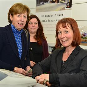 Plezier bij de kassa. Annemarie van Bracht (oud-medewerker), Monique Stoel (medewerker).