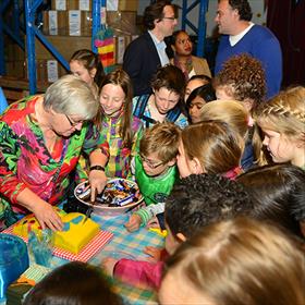 Eerst taart eten dan maar. Juf Margriet van Mameren snijdt de taart onder de ogen van haar oplettende pupillen.