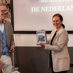 Auteur Frank Krake heeft zojuist het eerste exemplaar van zijn nieuwe boek 'De grootste bankoverval allertijden' overhandigd aan Nicole Stolk van De Nederlandsche Bank