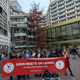 Met z'n allen tegen de boete op lezen. Achter het spandoek onder meer boekverkoper Fabian Paagman, ervoor zijn twee kinderen, verzonken in een boek