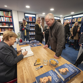 Angela Merkel tijdens het signeren.