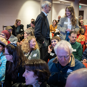 Aanwezigen nemen plaats in de aula van de KB